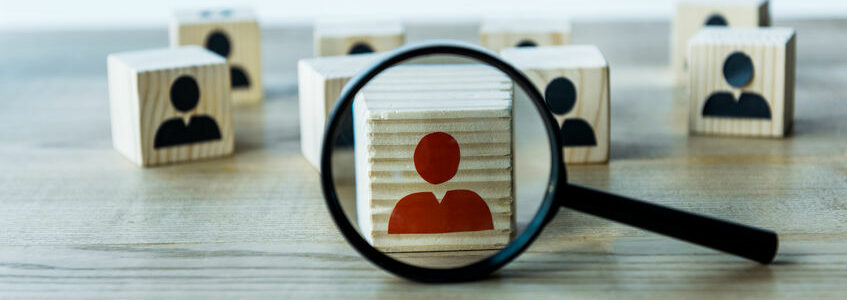 selective focus of magnifying glass near cubes on wooden desk