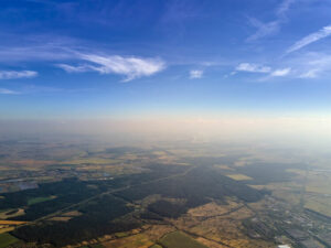 Aerial view of farm fields and distant scattered houses in rural area.