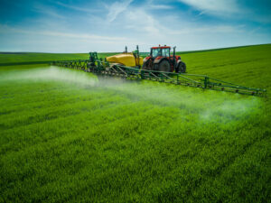 Aerial view of farming tractor plowing and spraying on field.