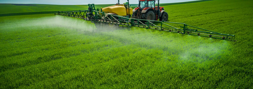 Aerial view of farming tractor plowing and spraying on field.