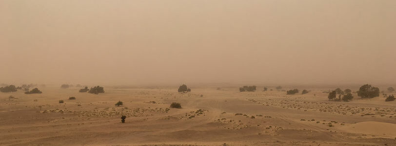 Sand storm in the Moroccan desert. Arid landscape where you can see the horizon and the reddish sky. Global warming.