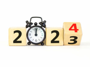 Business concept of 2024 new year symbol. Businessman turns a wooden cube and changes number 2023 to 2024. Black alarm clock. Beautiful white background, copy space. 2024 happy new year concept.